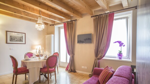 Een eetgedeelte met een tafel voor vier personen, een kroonluchter en een bank met uitzicht op een raam.