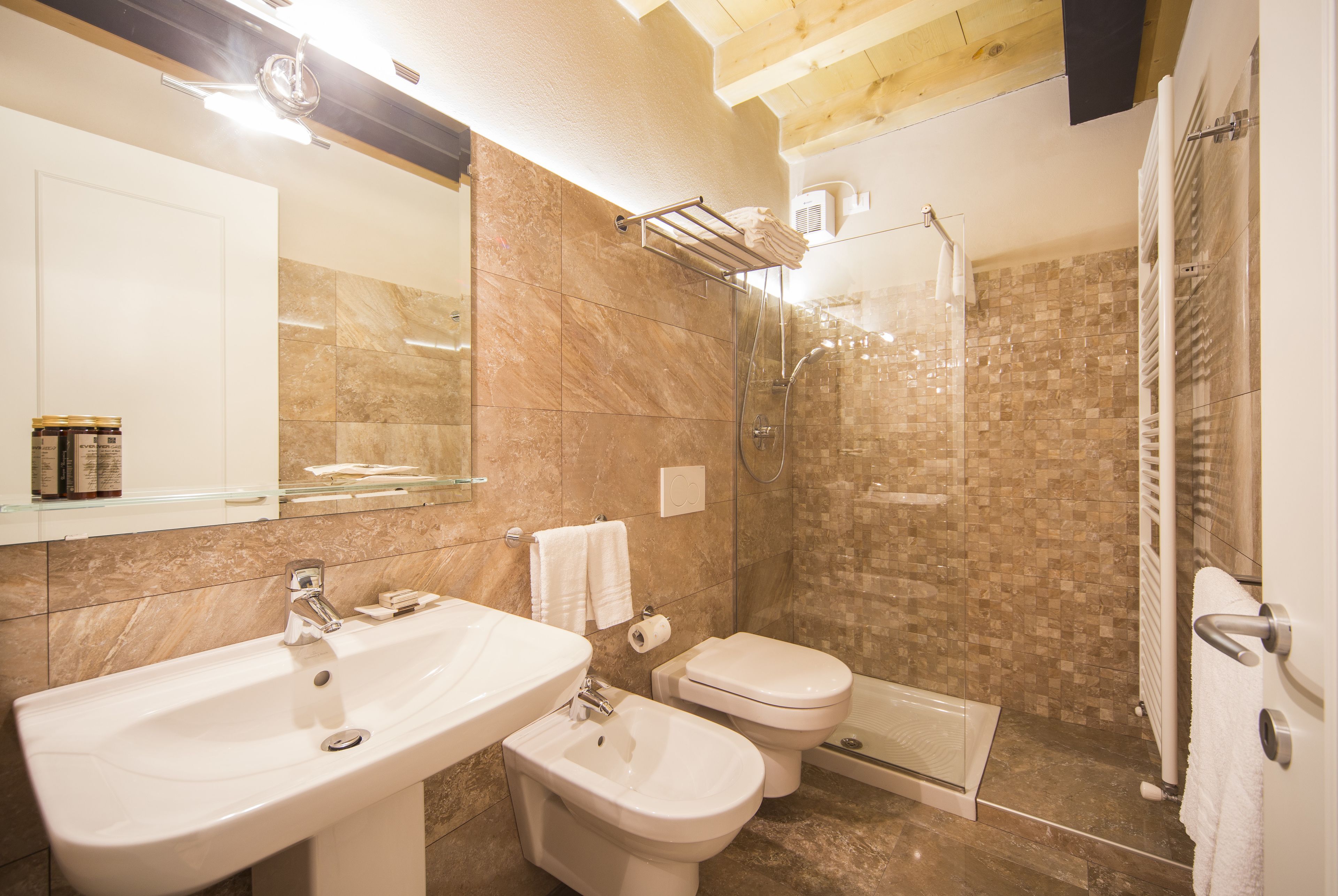 A bathroom with a sink, bidet, toilet, and glass-enclosed shower area.