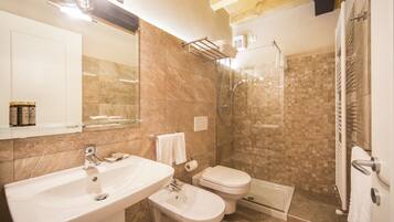 A bathroom with a sink, bidet, toilet, and glass-enclosed shower area.