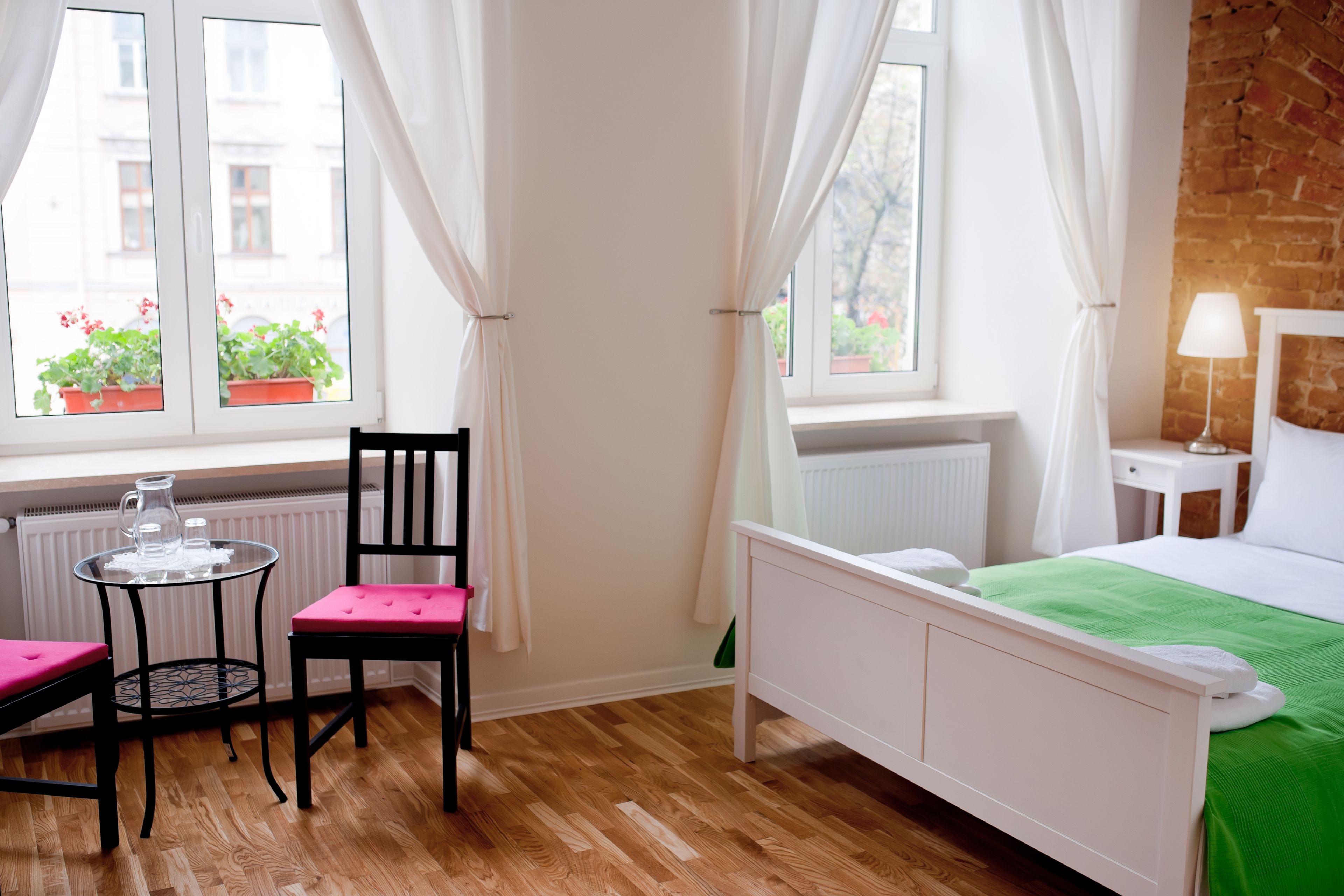 A room with a bed, a chair, a table, and a window with curtains.