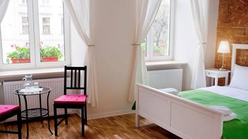 A room with a bed, a chair, a table, and a window with curtains.