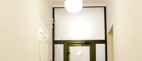 A hallway with wooden flooring, white walls, and a white ceiling light.