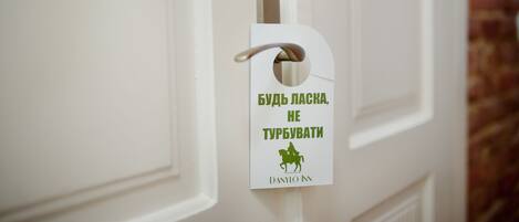 A door with a white doorbell and a sign that reads "БУДЬ ЛАСКА, НЕ ТУРБУВАТИ" and "DANYLO NN".