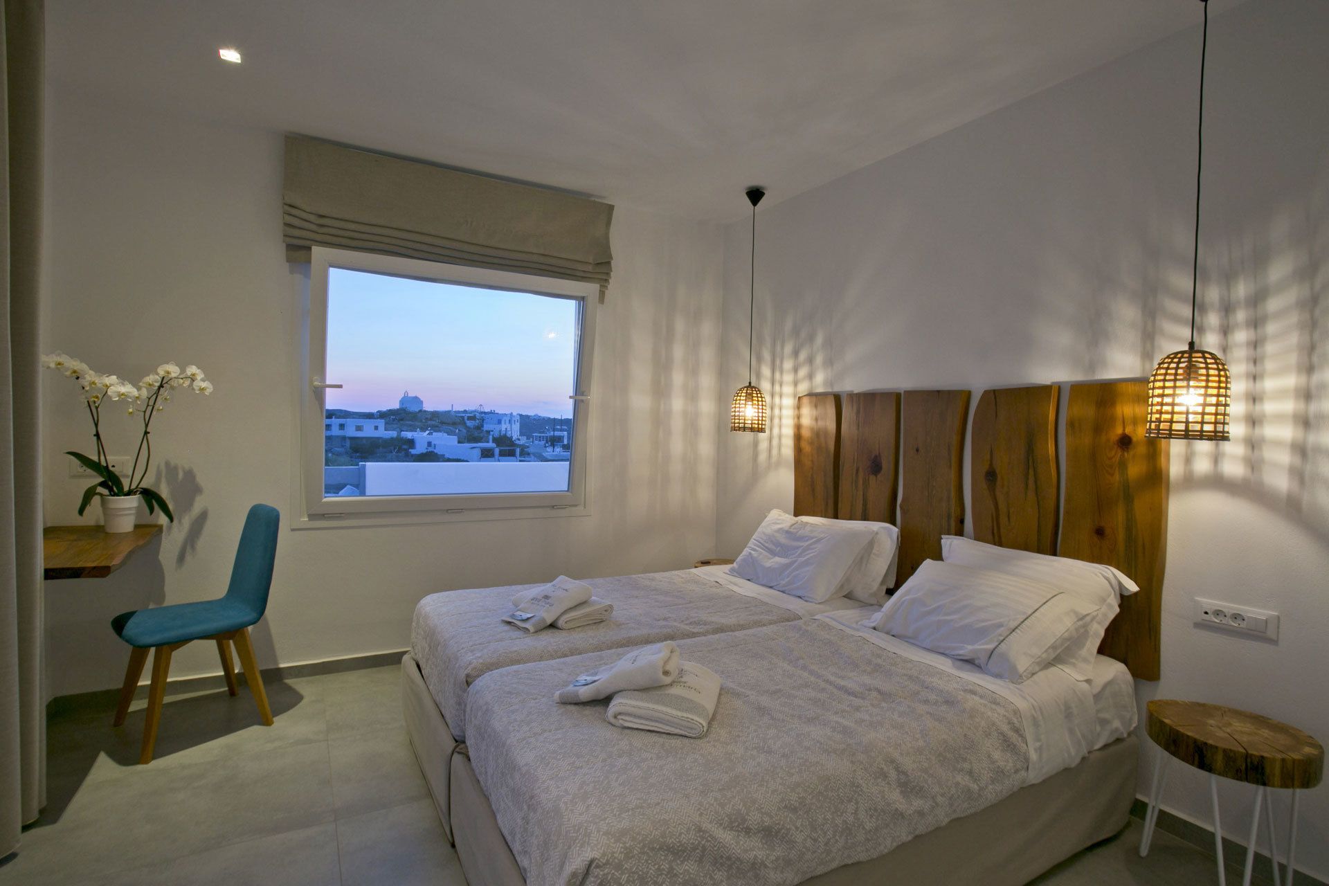 Un dormitorio con dos camas, una ventana con vistas, una silla y una mesita de noche.