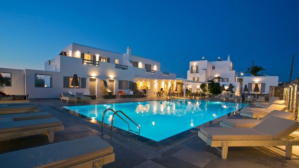 Un hotel moderno con piscina, tumbonas y zonas de estar al aire libre.