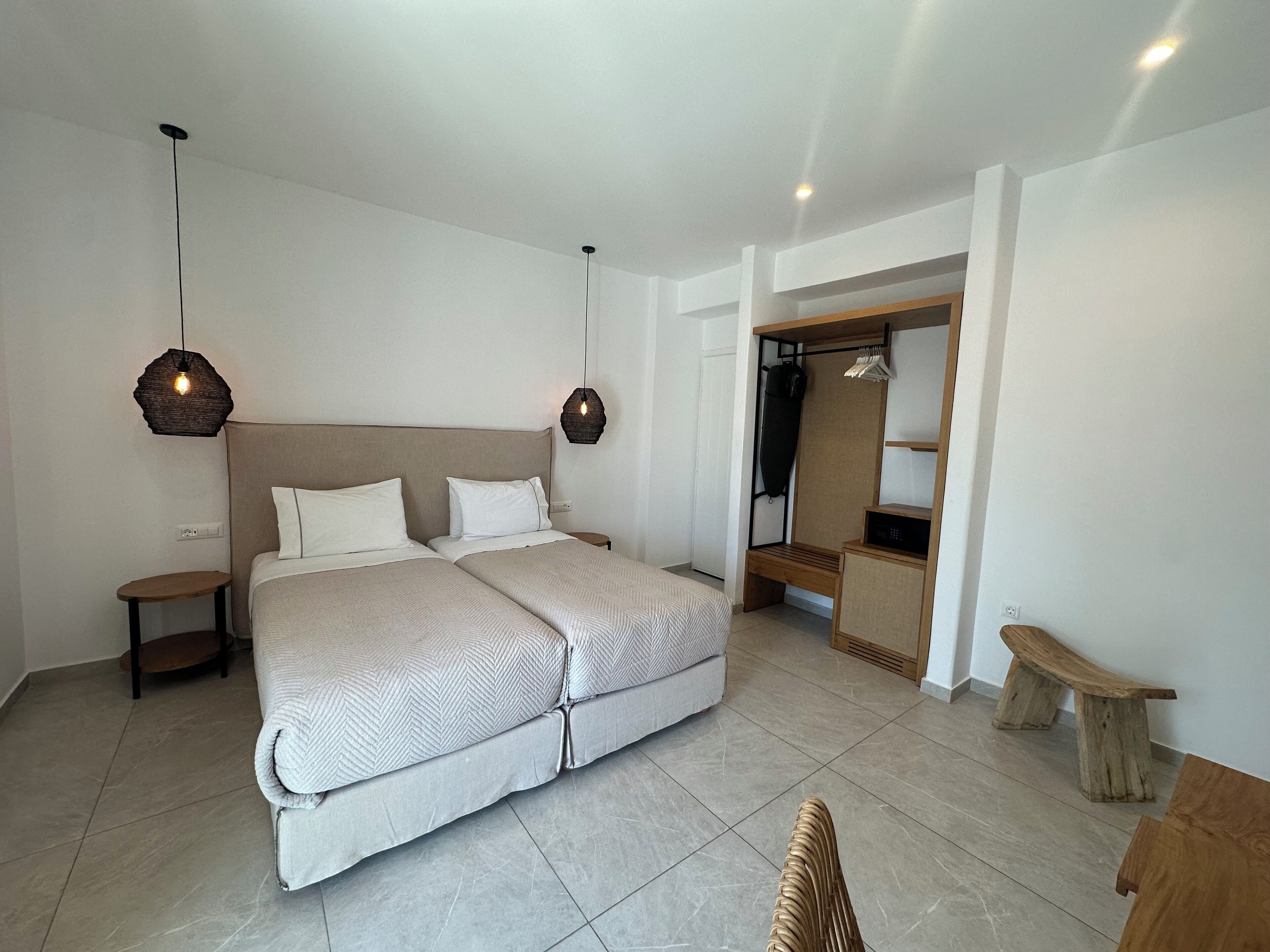 Quarto moderno com cama grande, mesas de cabeceira, guarda-roupa e um banco.