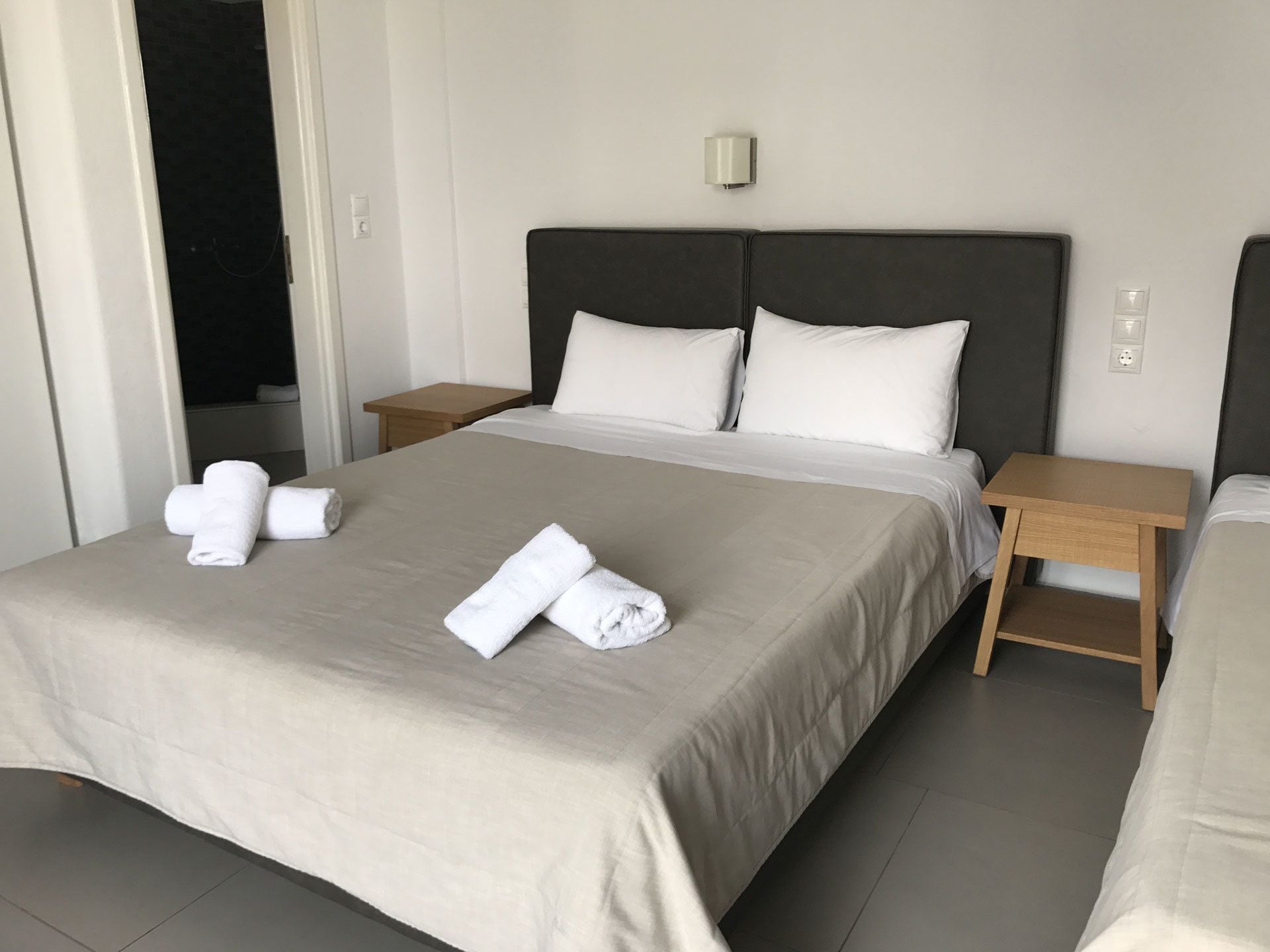 A hotel room with a large bed, two bedside tables, and a nightstand.
