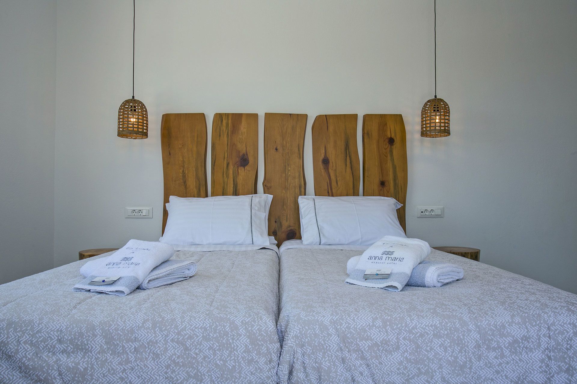 Ein Doppelbett mit hölzernem Kopfteil, zwei Nachttische und zwei Pendelleuchten.