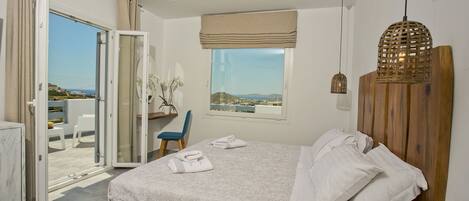 Un dormitorio con cama, una silla, una mesa y vista al mar.