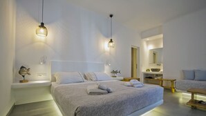 Un dormitorio moderno con una cama grande, mesitas de noche, un banco de madera y un baño con lavabo y espejo.