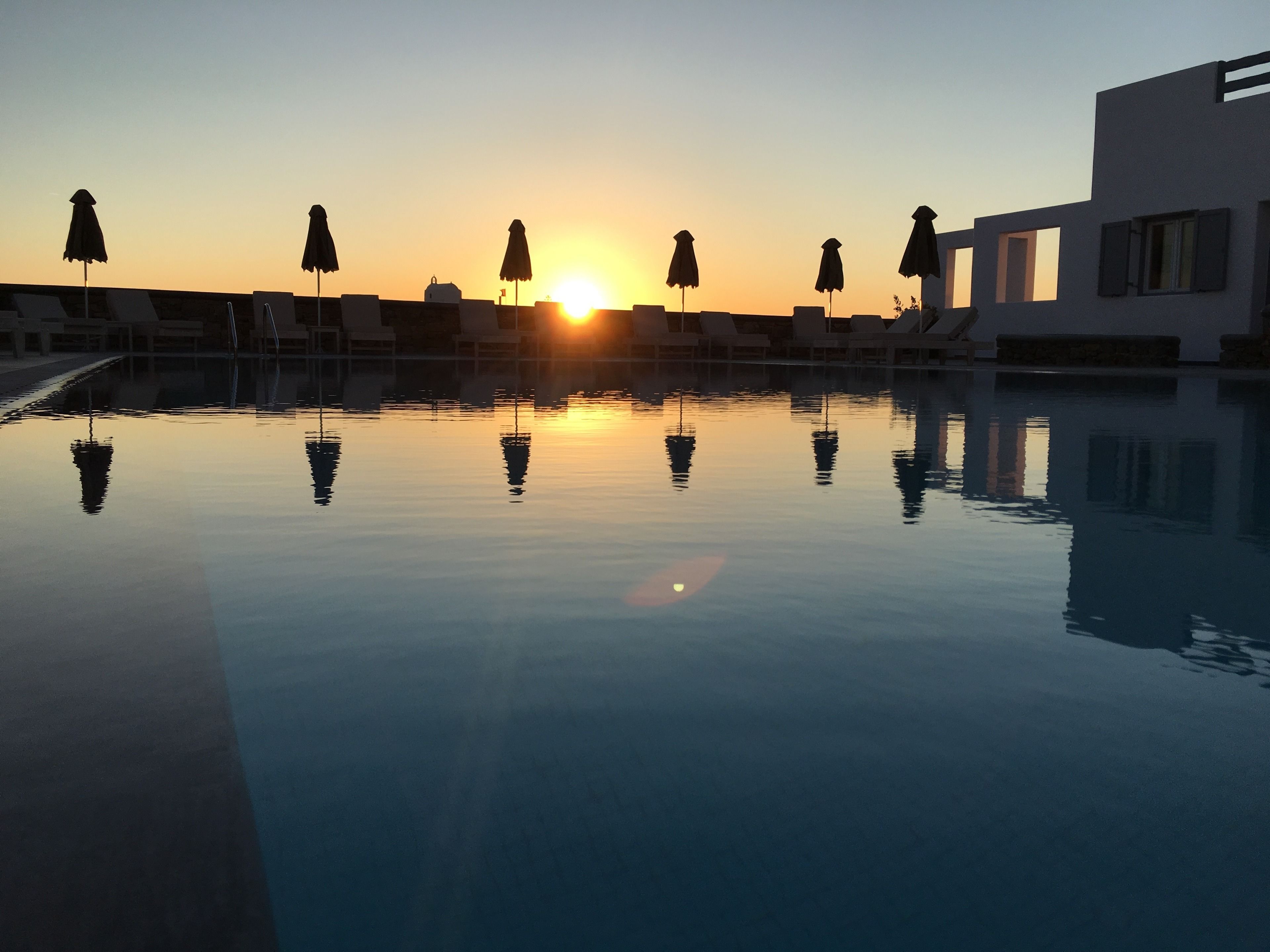 Een buitenzwembad, parasols bij het zwembad en ligstoelen