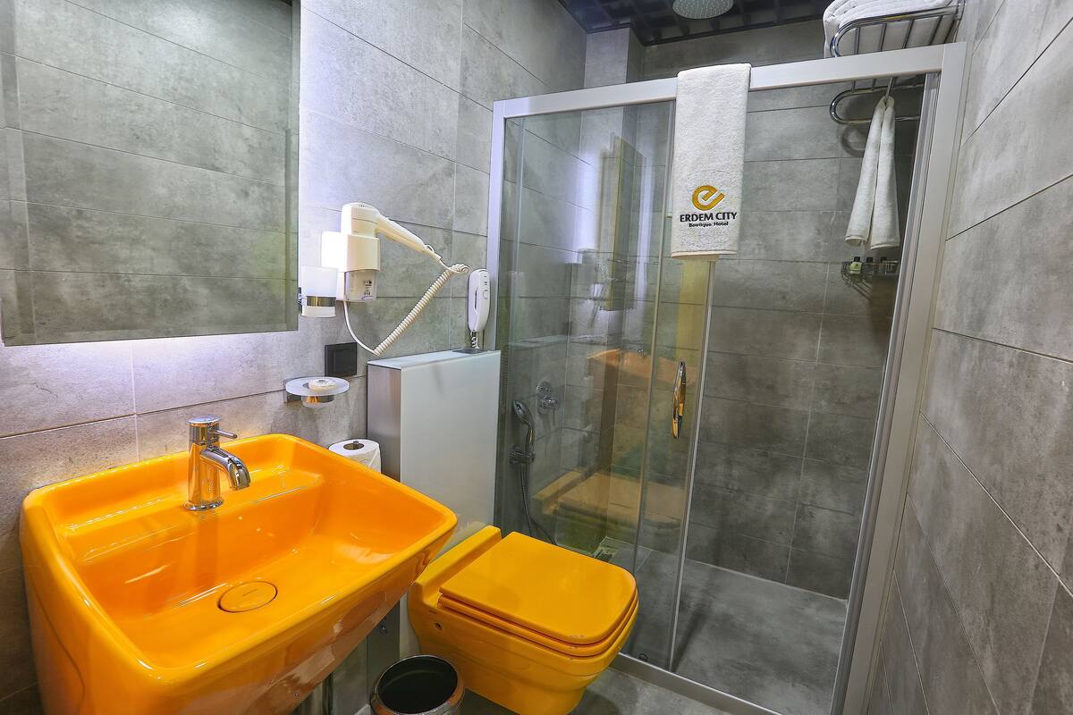 Ein Badezimmer mit Duschkabine aus Glas, einem gelben Waschbecken und einer Toilette.