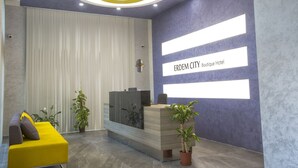 A modern reception area with a vertical panel wall, a reception desk, and a yellow sofa. - Erdem City Hotel (Kas)