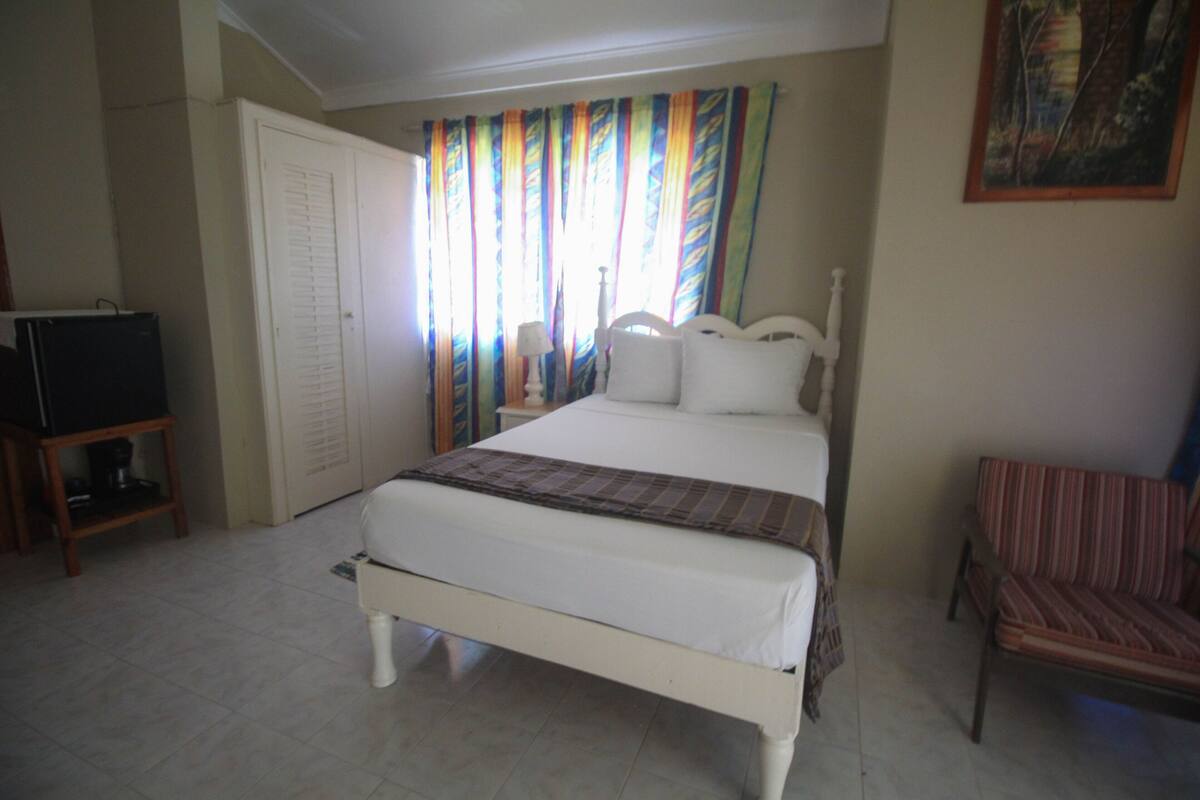 A bedroom with a bed, a chair, a wardrobe, and a television.