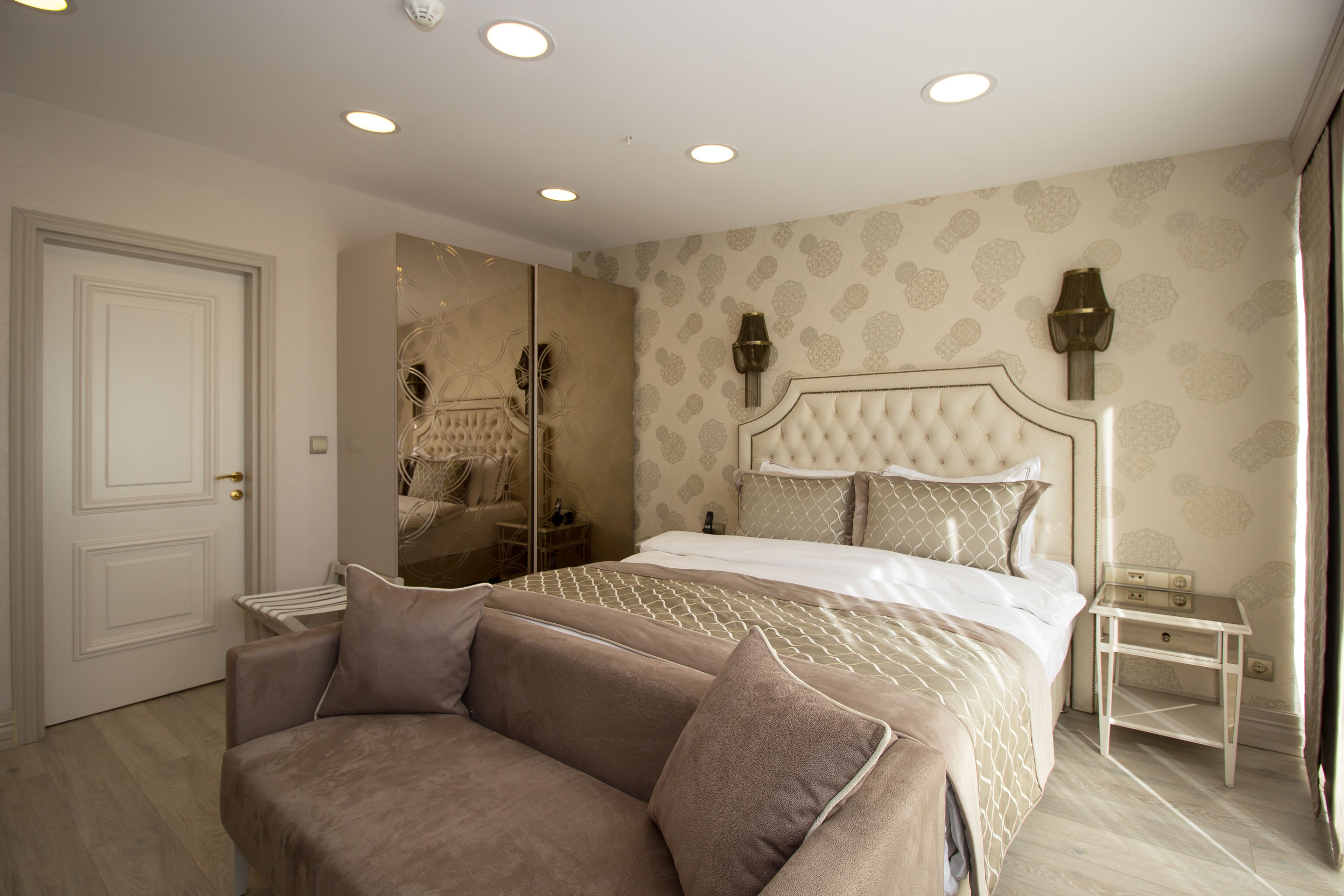 Une chambre à coucher avec un grand lit, un canapé, une table de chevet et un miroir.