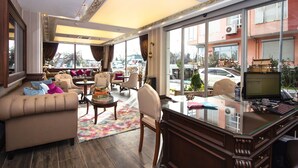 A spacious hotel lobby with a comfortable seating area, a desk with a computer, and large windows offering a view of the street. - Le Marde Hotel (Istanbul)