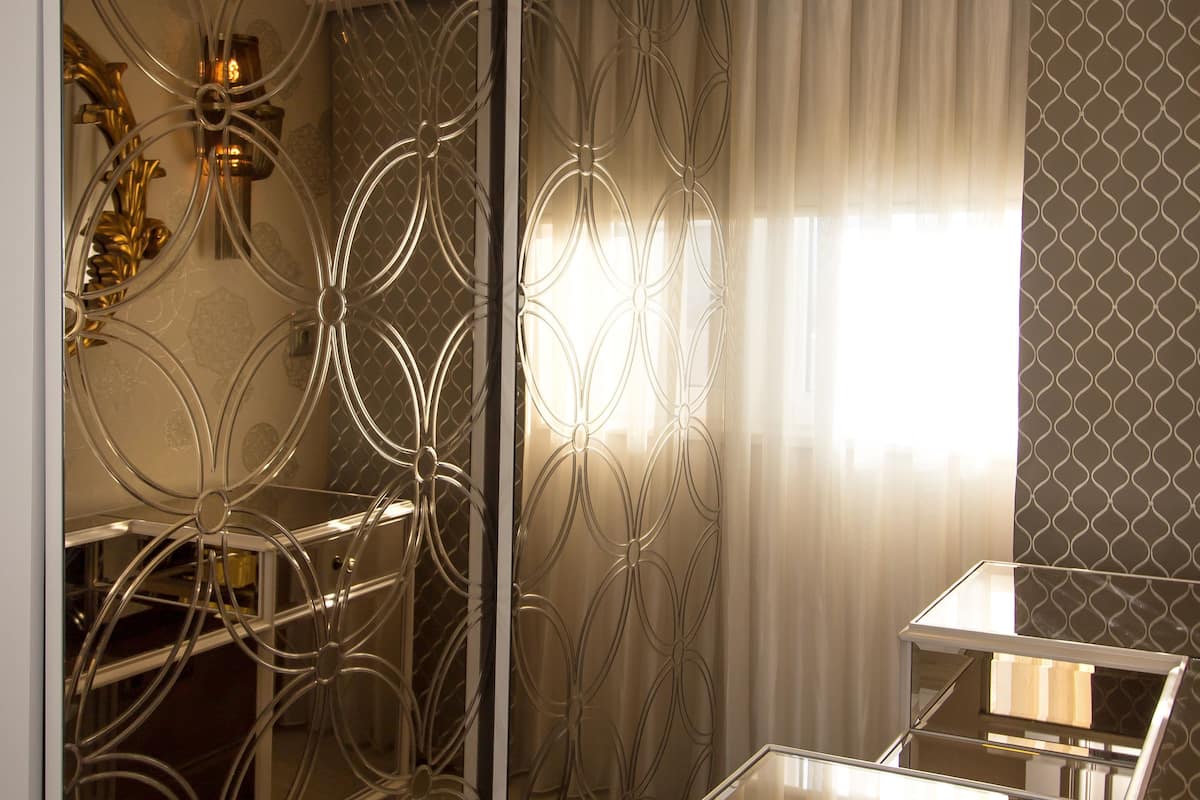 A modern bathroom with a glass shower enclosure, a vanity with a mirror, and a patterned wall.