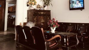 Un comedor con techo de madera, un candelabro, un televisor montado en la pared y una mesa de comedor con sillas.