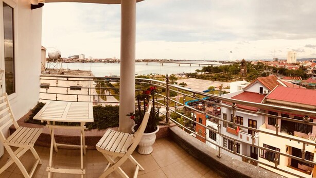 Un balcón con mesa y sillas, con vista a un río y al paisaje urbano.