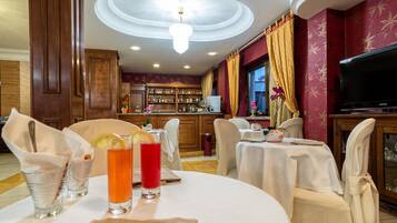 Ein Restaurant mit runden Tischen, Stühlen, einer Bar mit Flaschenregalen und einem Fernseher.