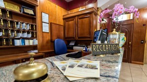 A reception desk with a 'RECEPTION' sign, a bell, and a computer monitor. - Hotel Ristorante Donato (Calvizzano)