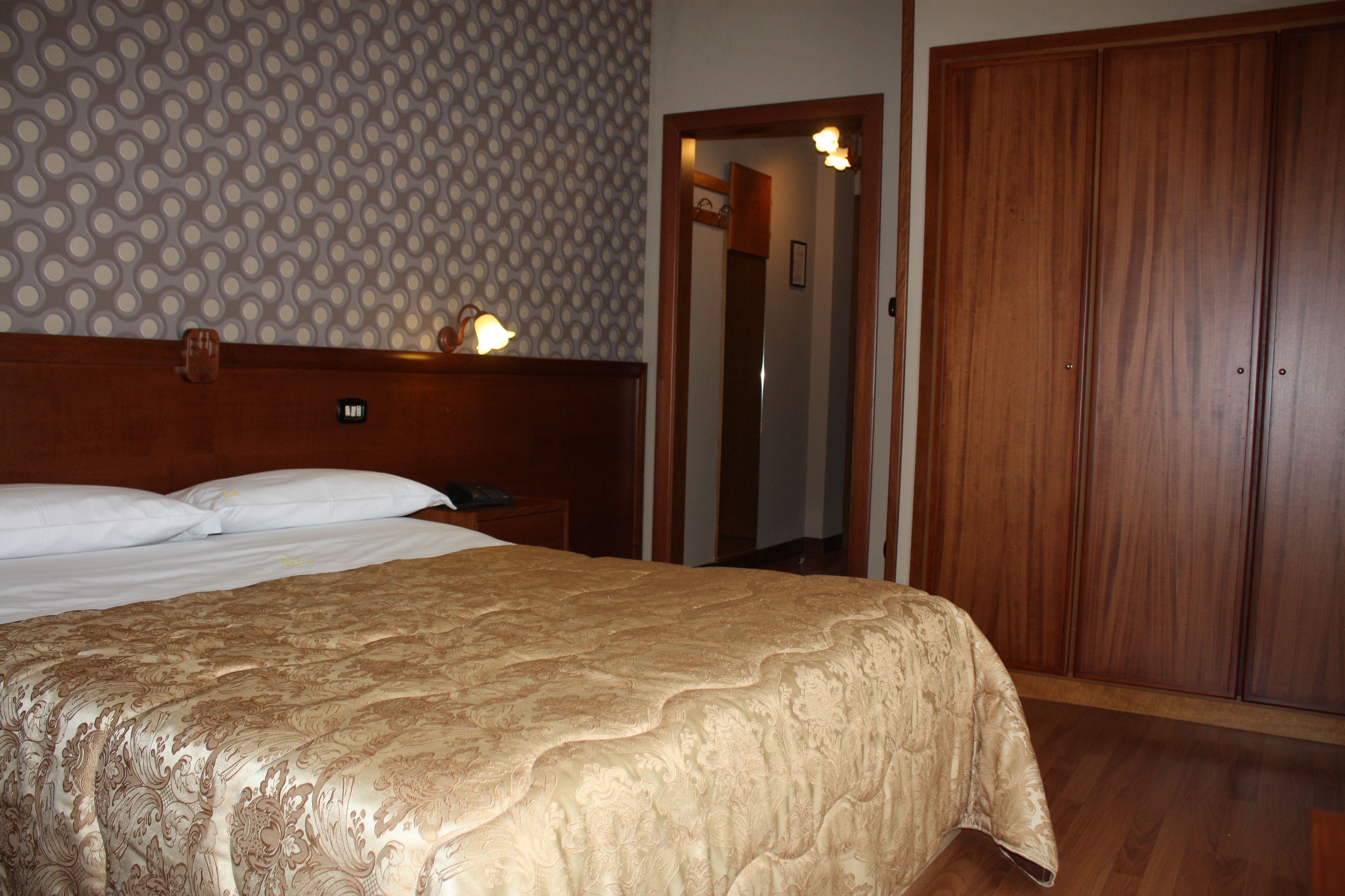 Una habitación de hotel con una cama grande, un armario de madera y una pared con diseño.