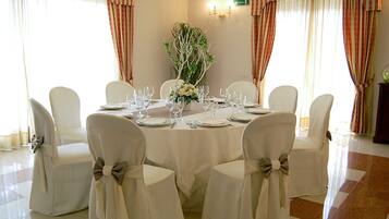 A dining area with a round table set for six, surrounded by six chairs with bow ties.