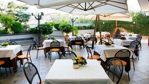 An outdoor patio with tables and chairs, covered by umbrellas, and surrounded by greenery. - Hotel Ristorante Donato (Calvizzano)