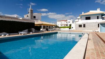 Een buitenzwembad, parasols voor strand/zwembad