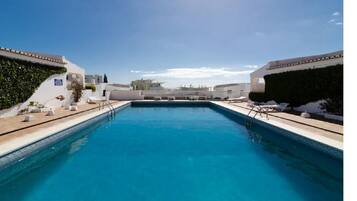 Una piscina al aire libre, sombrillas, tumbonas