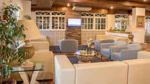A hotel lobby with seating areas, a television, and a decorative wall. - Aparthotel Calema Avenida Jardim (Vila Real Santo Antonio)