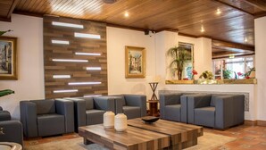 A modern living room with grey sofas, a wooden coffee table, and a decorative wall panel. - Aparthotel Calema Avenida Jardim (Vila Real Santo Antonio)