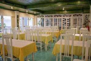 A dining area with white chairs and yellow tablecloths, arranged in rows. - Aparthotel Calema Avenida Jardim (Vila Real Santo Antonio)