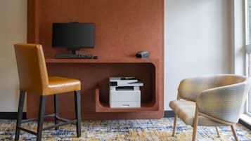 A modern room with a desk, two chairs, a flat-screen TV, a printer, and a window with a view.