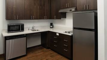 Una cocina moderna con armarios de madera oscura, electrodomésticos de acero inoxidable y una encimera blanca.