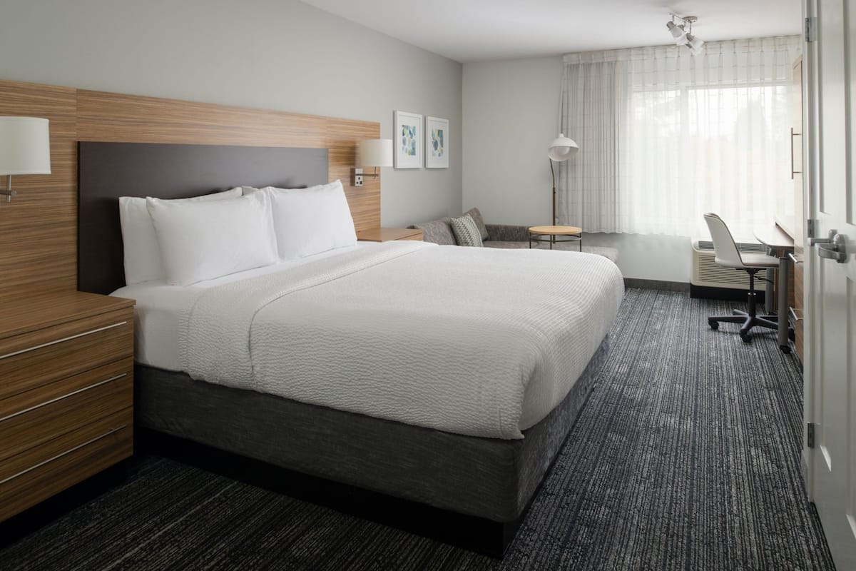 Hotellihuone, jossa on suuri sänky, työpöytä, tuoli ja pieni pöytä.