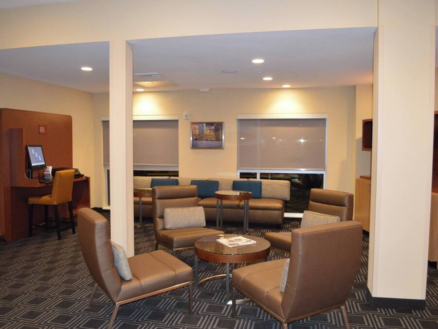 A hotel lobby with a seating area, a reception desk, and a small bar.