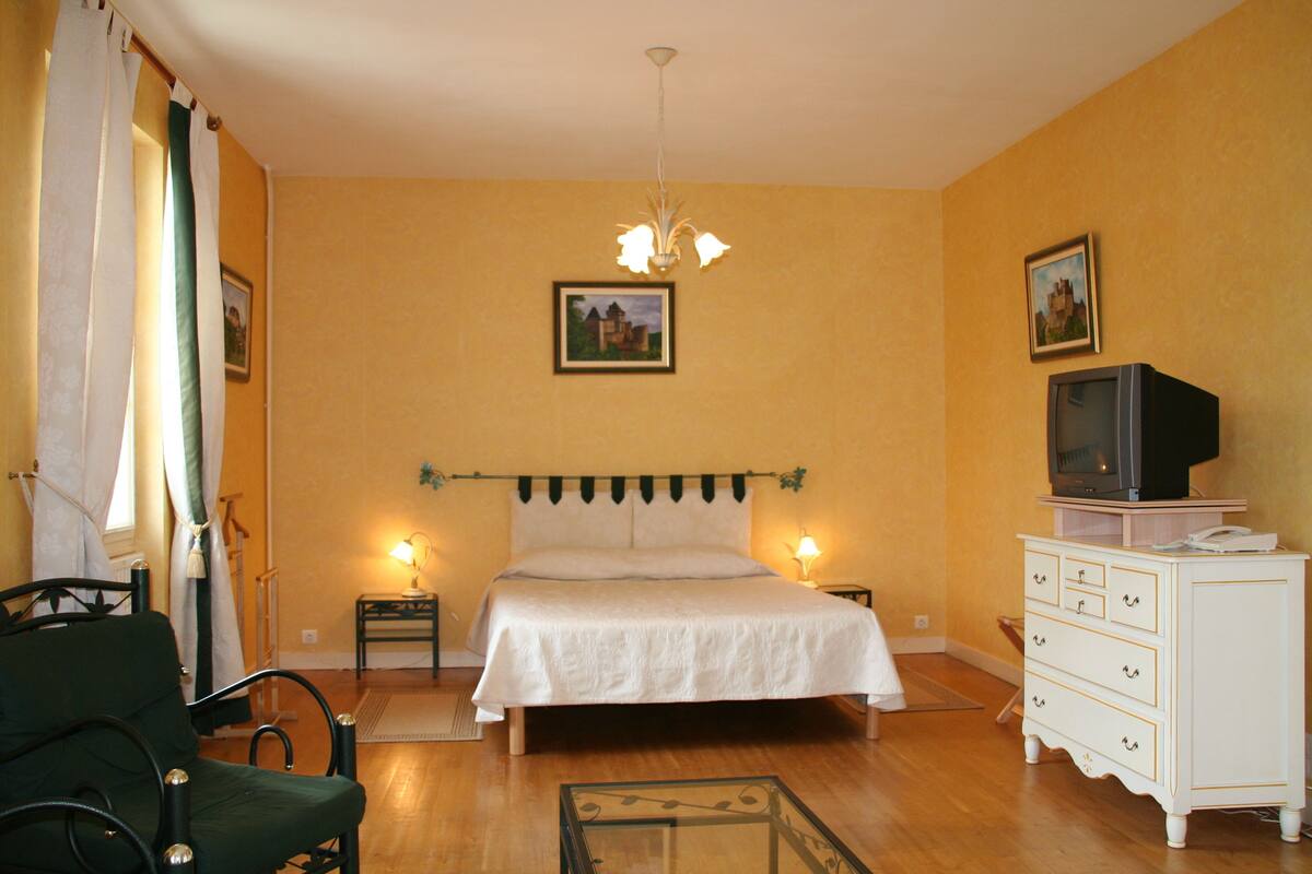 A bedroom with a bed, a dresser, a television, and two wall-mounted lamps.