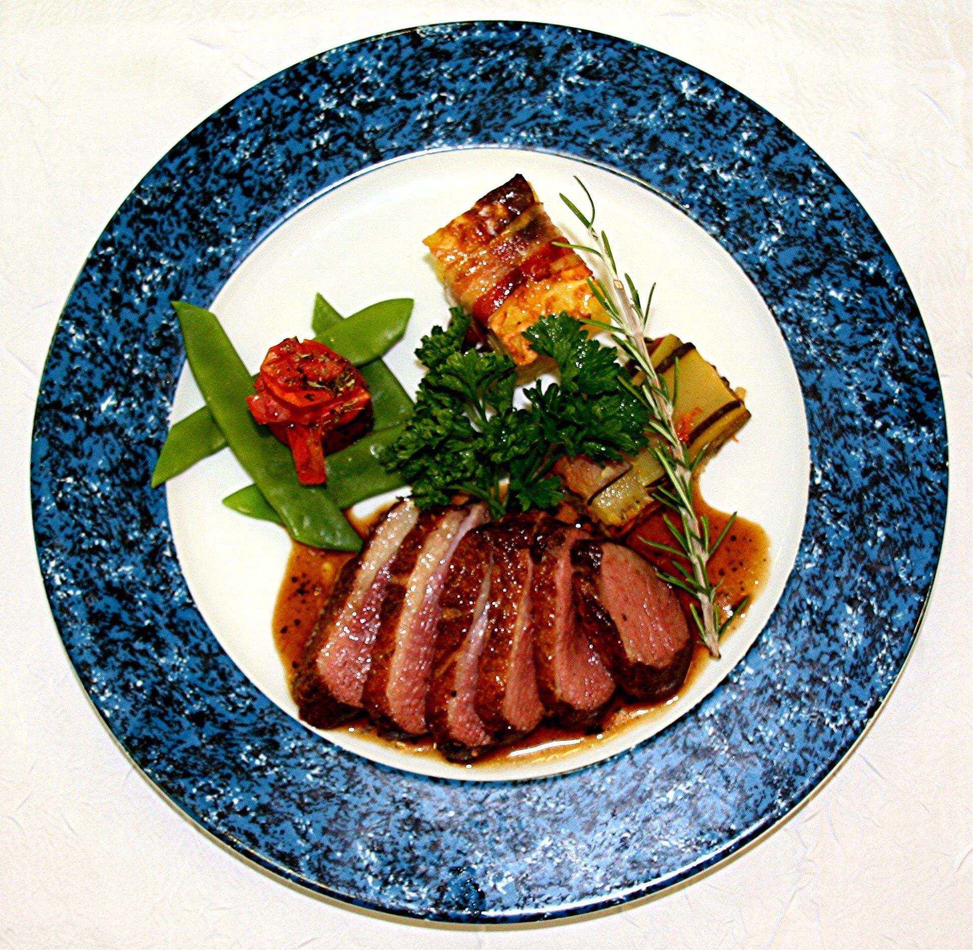 Un plato con carne en rodajas, verduras y hierbas aromáticas.