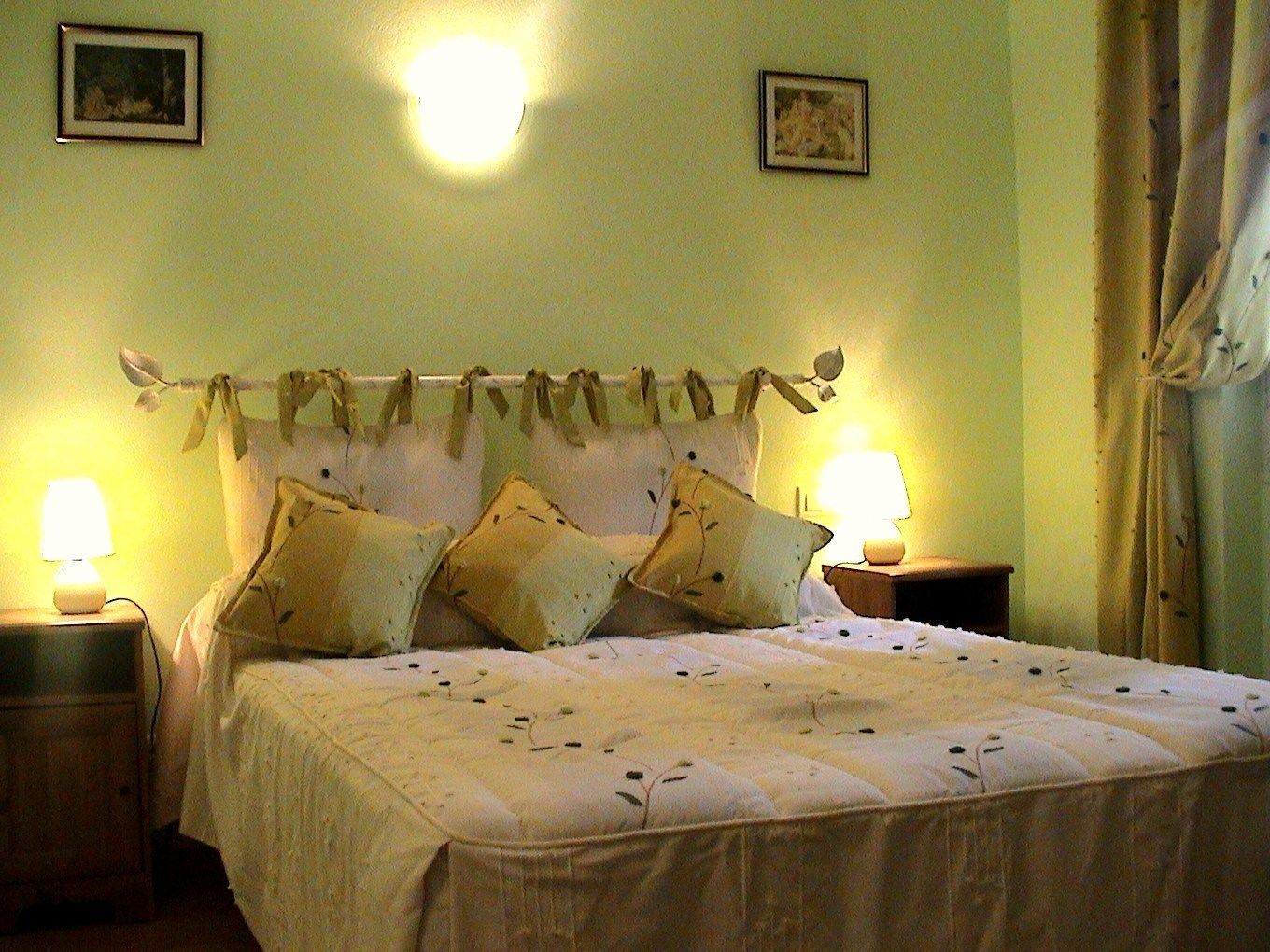 A bed with a headboard decorated with branches, two bedside lamps, and a floral-patterned bedspread.