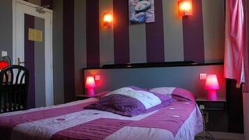 Una habitación de hotel con una cama, dos lámparas de noche, una silla y una puerta.
