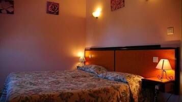 Habitació d'hotel amb un llit, dues làmpades laterals i decoració floral a la paret.
