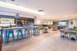 A spacious cafe with a bar area, multiple seating options, and a visible menu board. - Premier Inn Basingstoke Town Centre (Basingstoke)