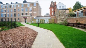 A brick building with multiple windows, a pathway, and a grassy area.