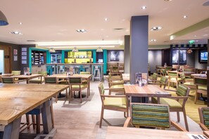A restaurant with wooden tables and chairs, a bar area, and a television screen. - Premier Inn Bury St Edmunds Town Centre (Bury St Edmunds)