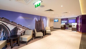 A hotel lobby with seating, a check-in counter, a television, and a wall mural.