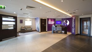 En hotellobby med en receptionsdisk, en tv och en skylt för Premier Inn.