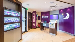 Een hotel receptie met een incheckbalie, een folderdisplay en een 'Premier Inn' bord.