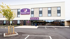 Een Premier Inn hotel met een moderne gevel, grote ramen en een parkeerplaats ervoor.