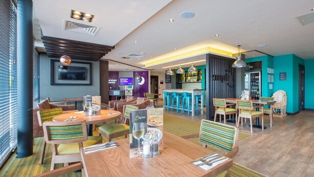 Een hotel lobby met een bar, zitgedeeltes en een televisiescherm.